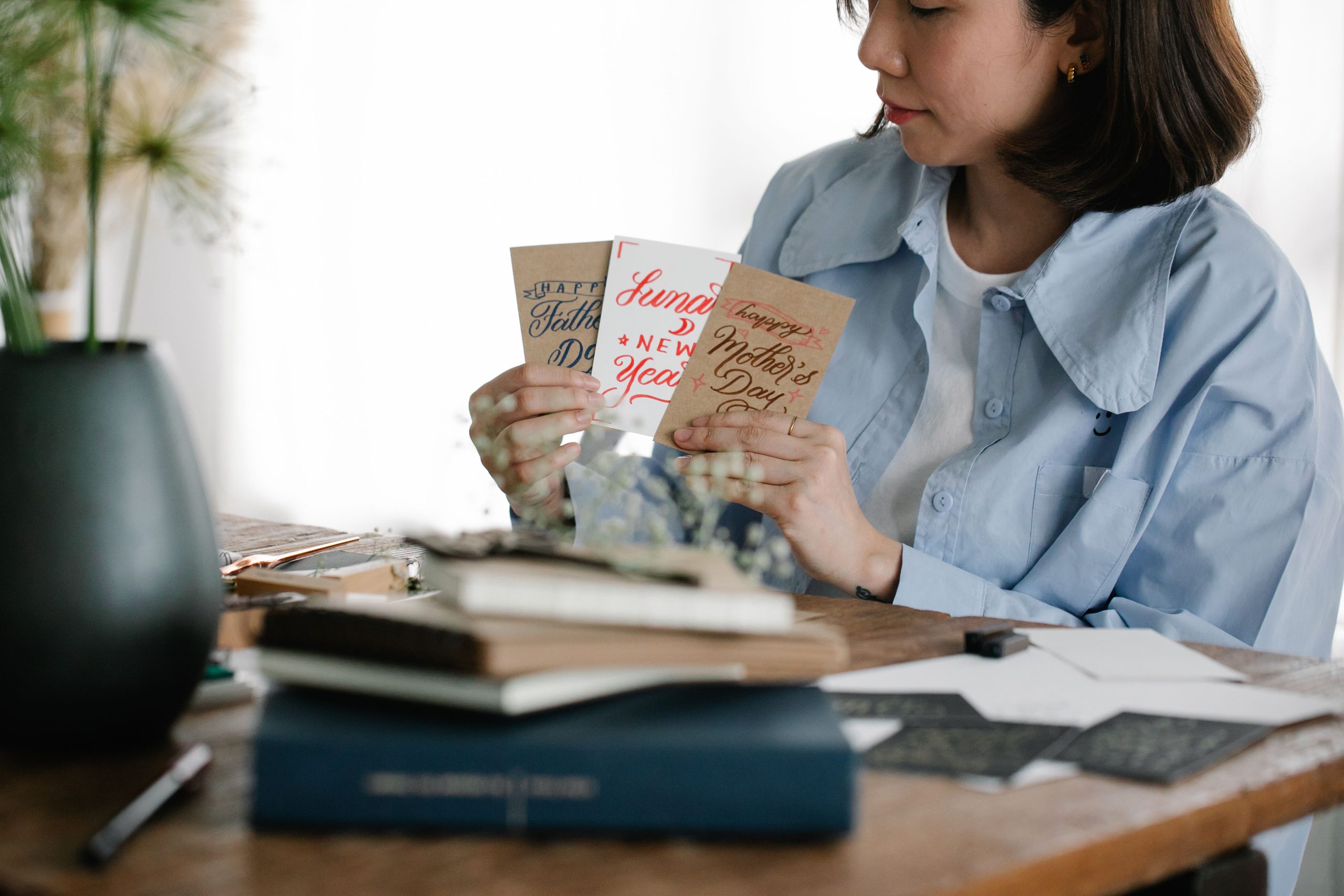 Woman choosing handmade greeting cards at a table, illustrating the paper-card foundation of a DIY audio greeting card.